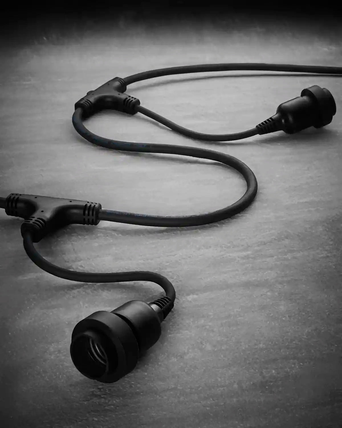 Black connectable festoon belt showing multiple long drop E27 sockets on a grey surface.