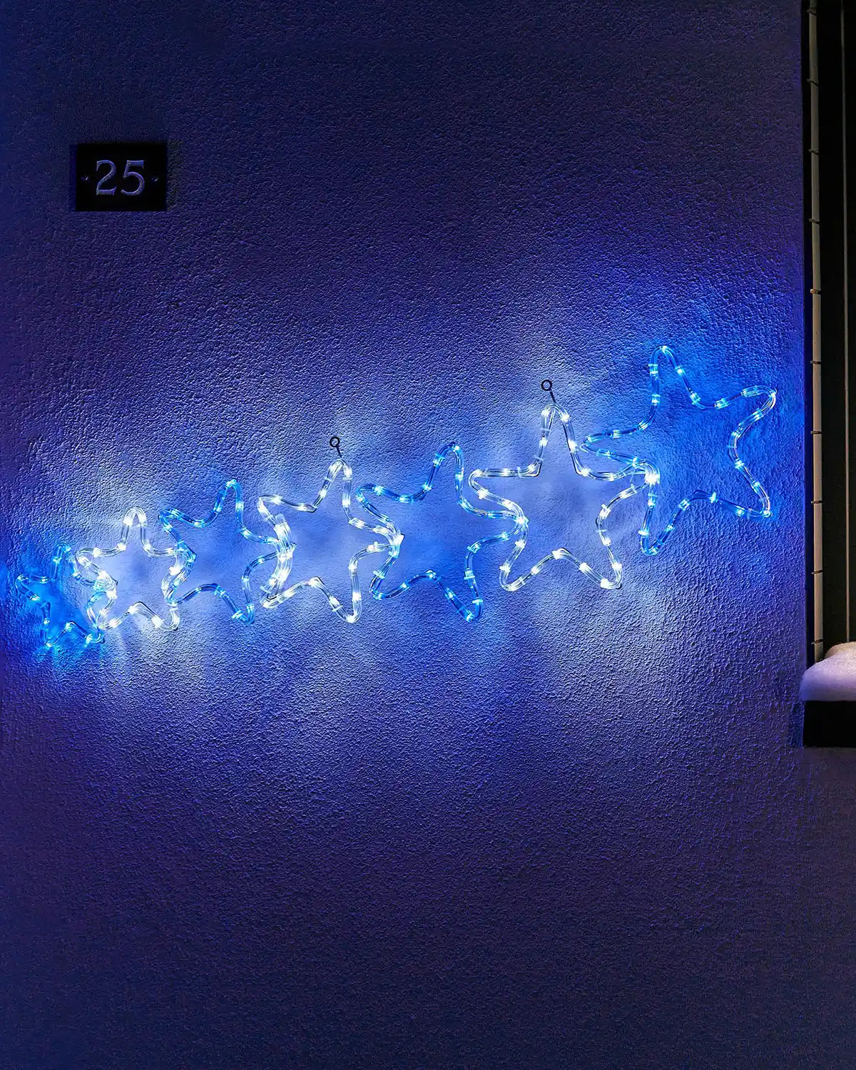 White and blue 7-star rope light silhouette displayed on an exterior wall