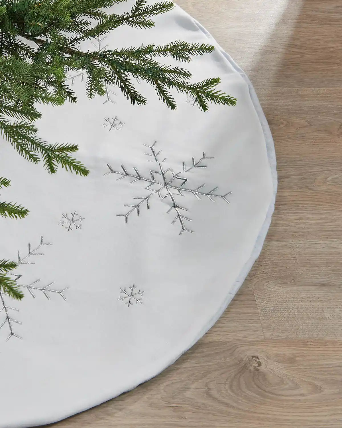 Close-up of a white 122 cm Christmas tree skirt with silver snowflake embroidery