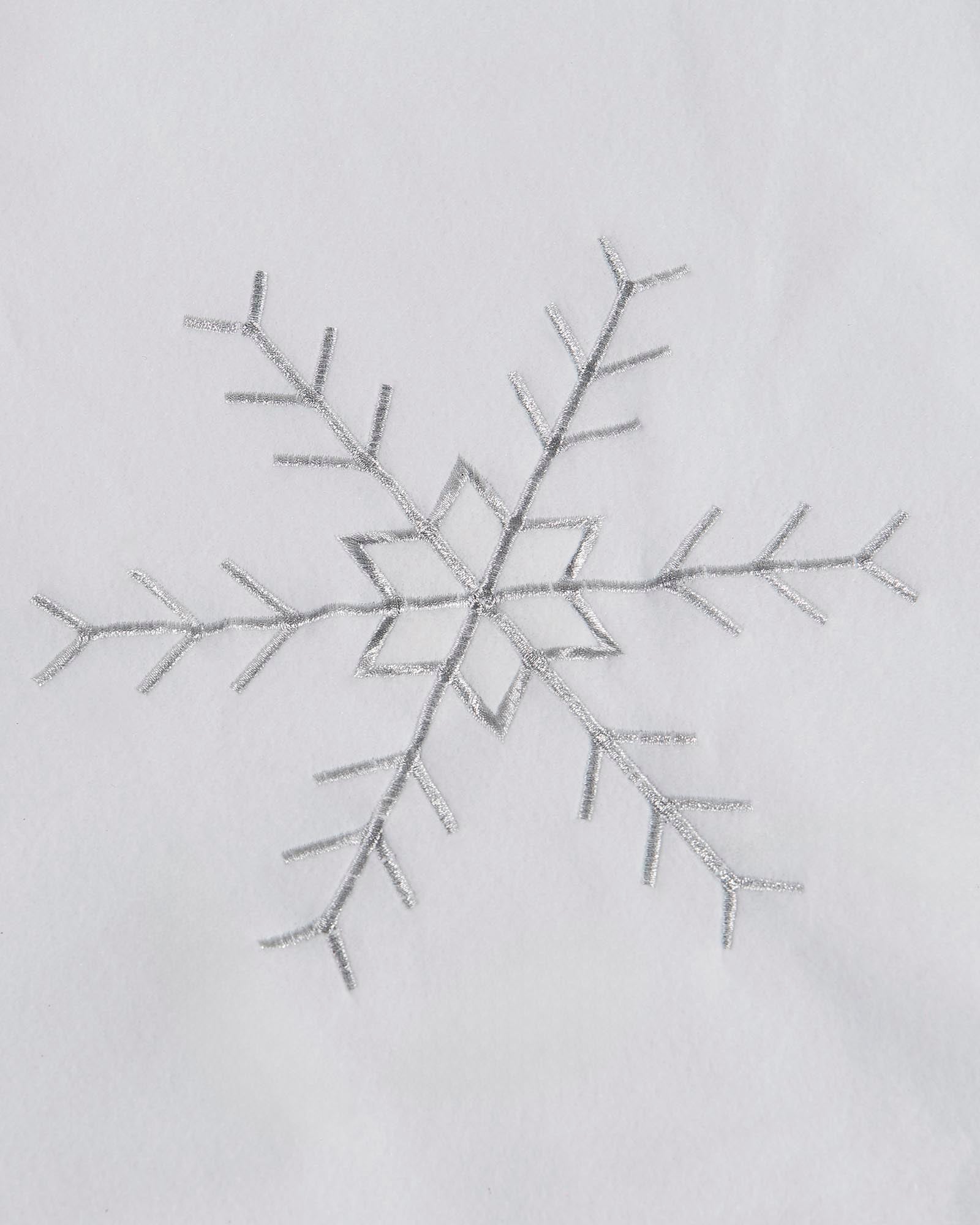 Close-up of silver embroidered snowflake detail on a white Christmas tree skirt