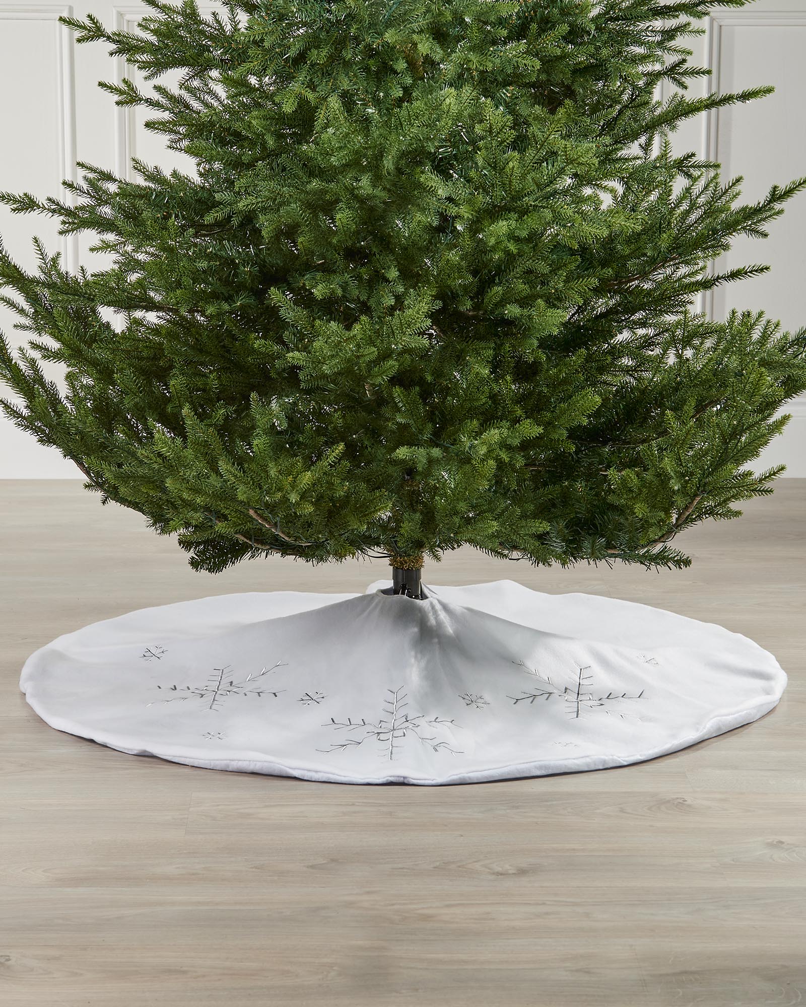 White snowflake Christmas tree skirt displayed around the base of a tree