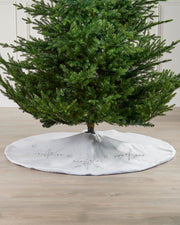 White snowflake Christmas tree skirt displayed around the base of a tree