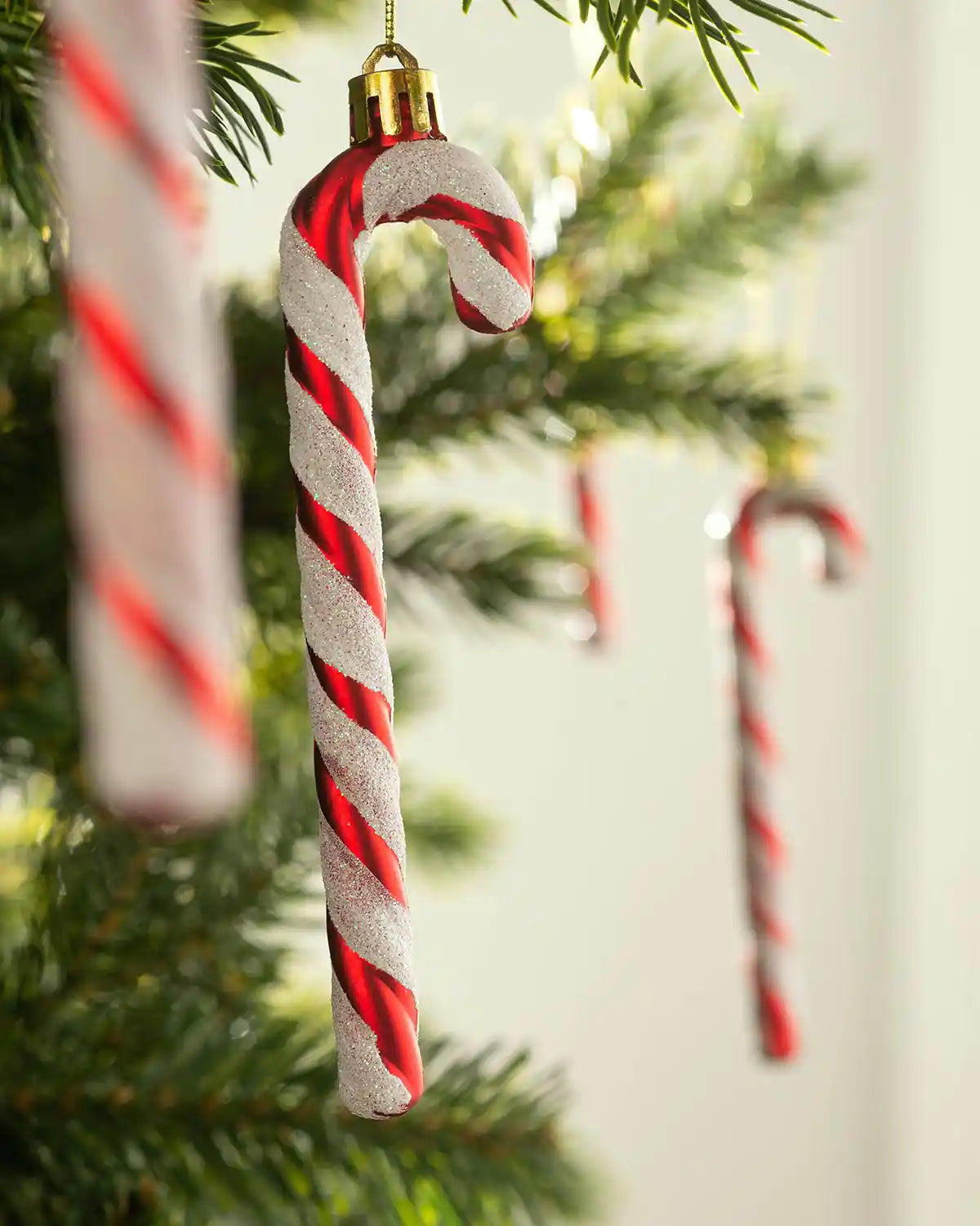 Close-up of a red and white shatterproof candy cane bauble with glitter detail