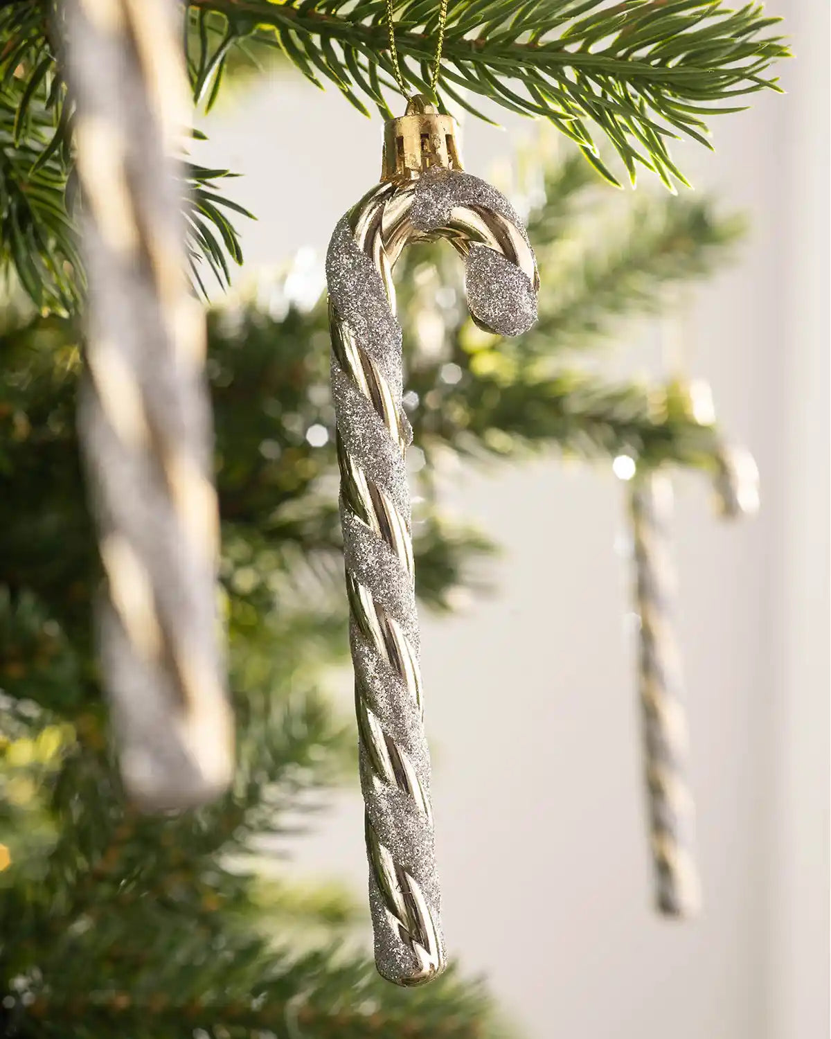 Close-up of a 13cm gold and white candy cane bauble hanging on a Christmas tree