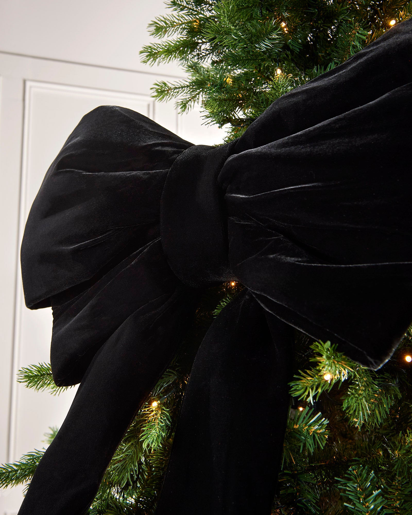 Close-up of a large black velvet Christmas bow on a Christmas tree
