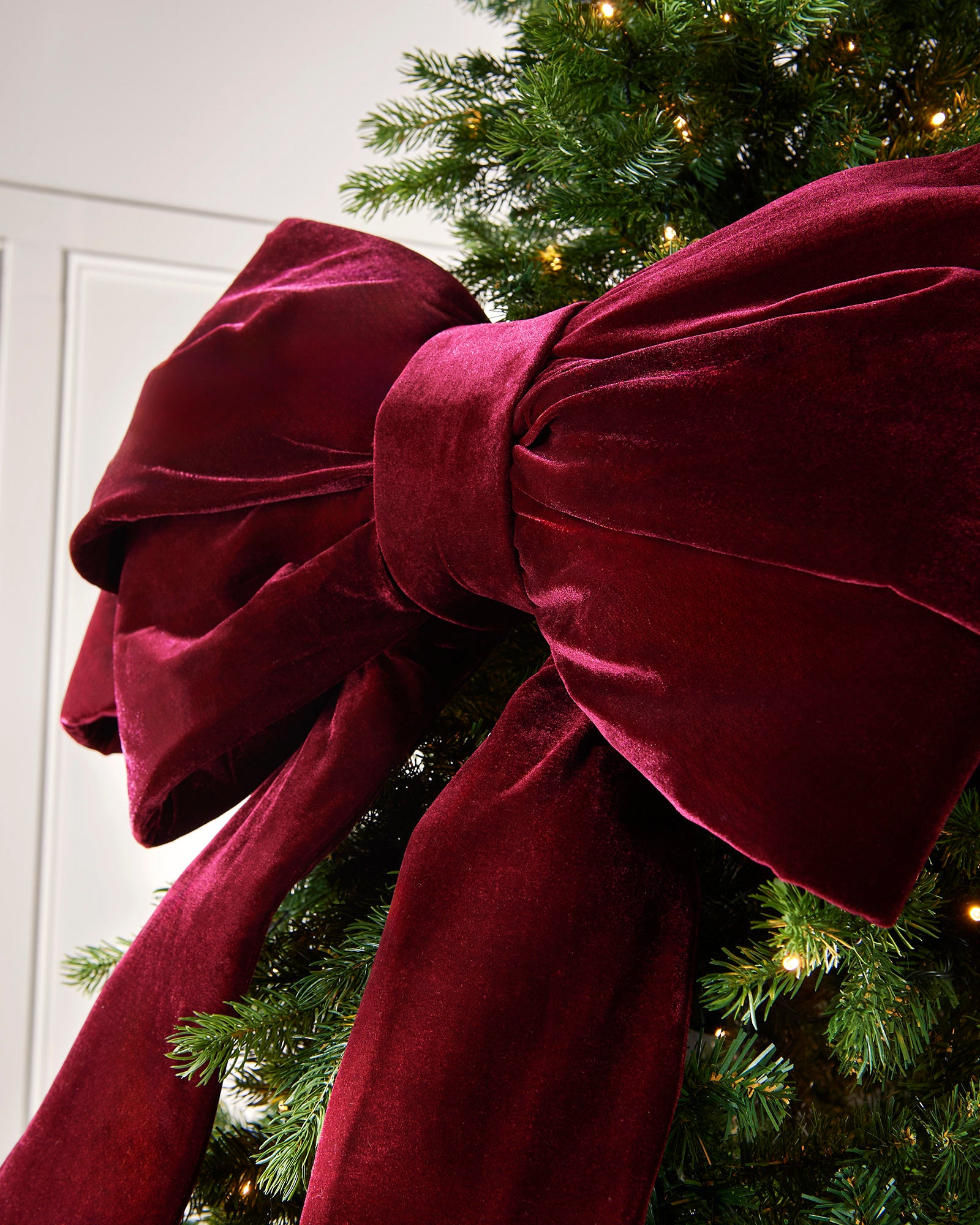 Close-up of a large burgundy velvet Christmas bow on a Christmas tree