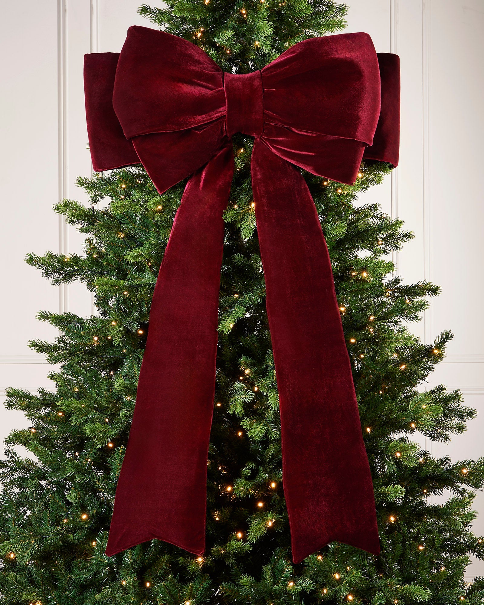 Large 140cm burgundy velvet Christmas bow displayed on a lit Christmas tree
