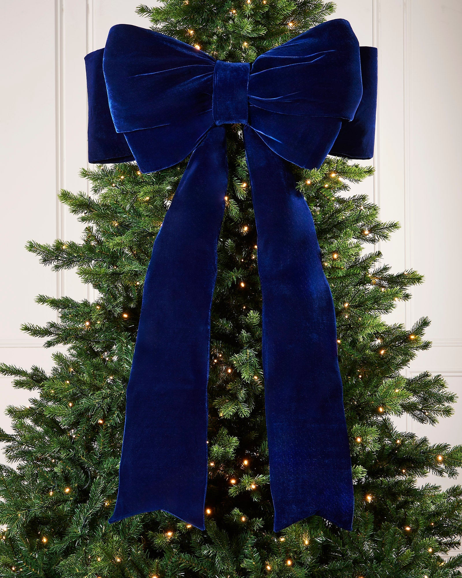 Large 140cm navy velvet Christmas bow displayed on a lit Christmas tree