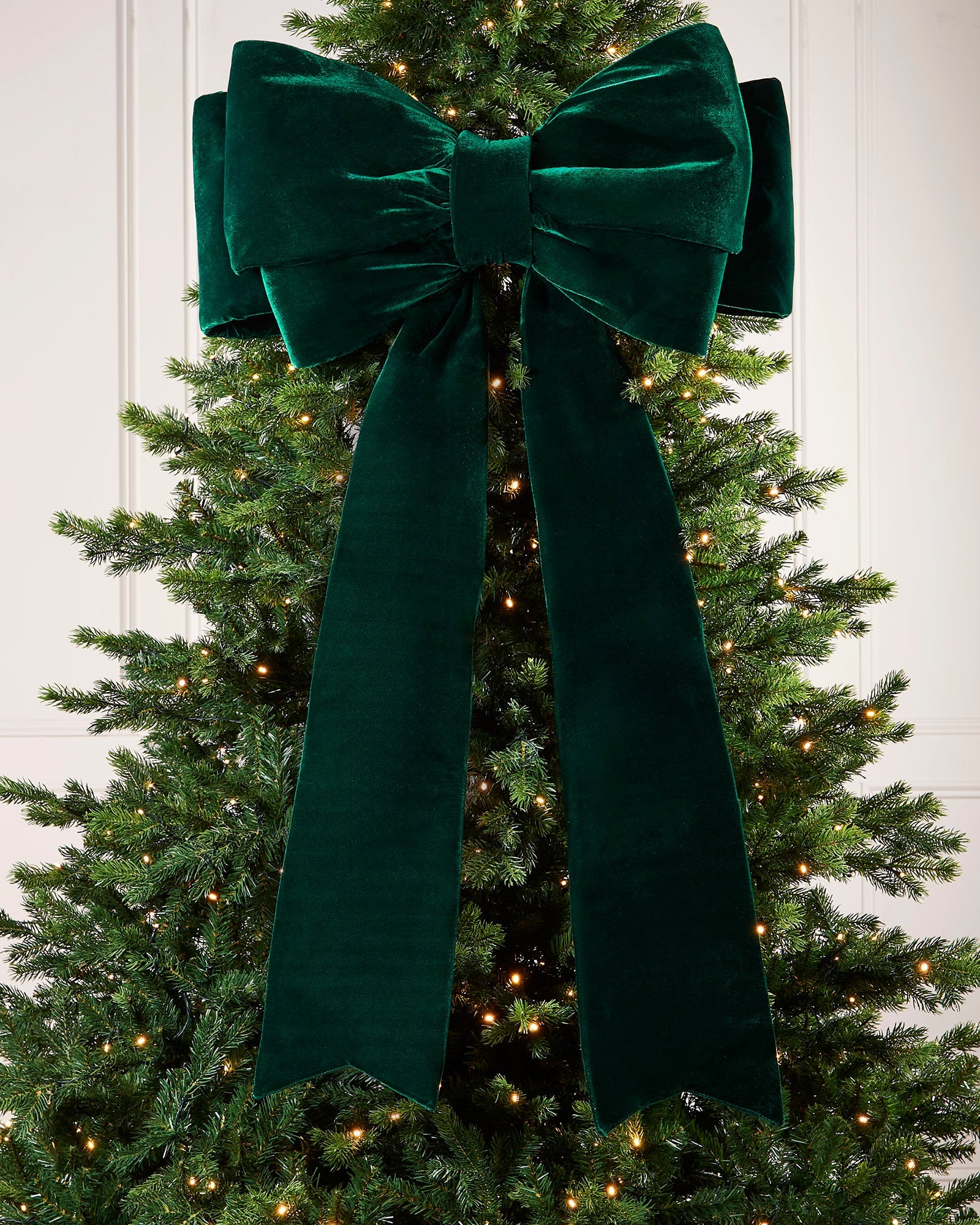 Large 140cm sage green velvet Christmas bow displayed on a lit Christmas tree