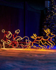 Santa sleigh and reindeer rope light silhouette glowing outdoors in warm white and red