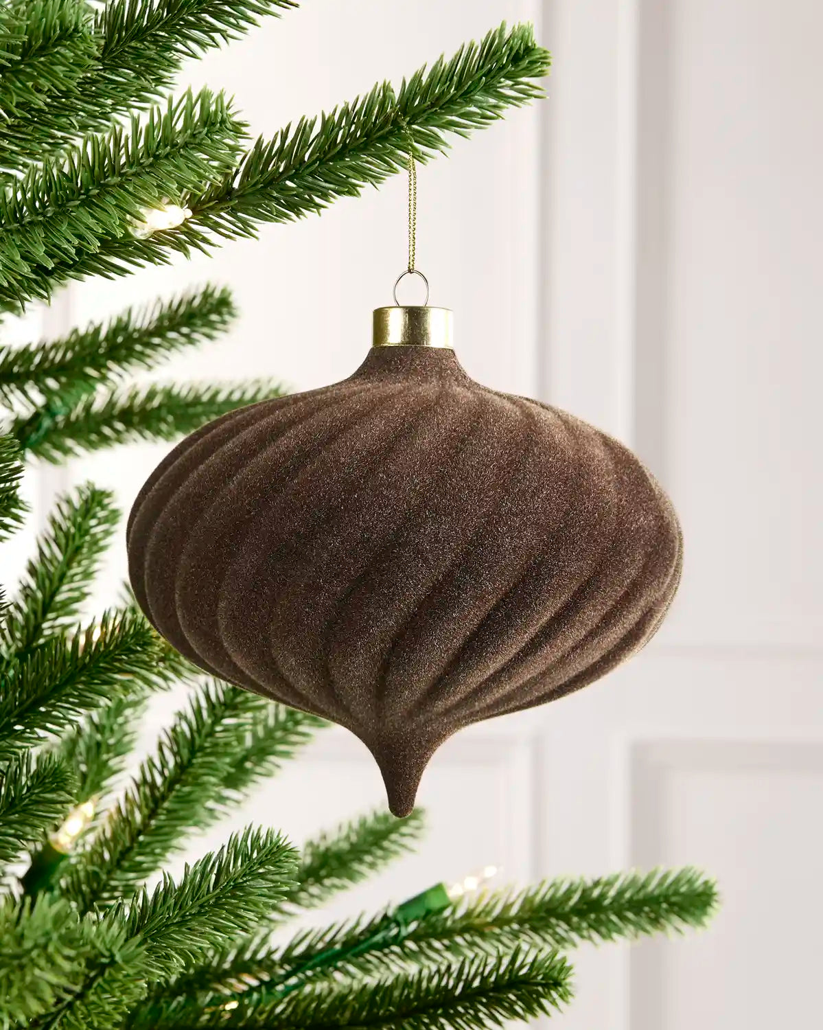 15 cm Mocha oversized velvet Spiral bauble hanging from a Christmas tree with a gold cap.
