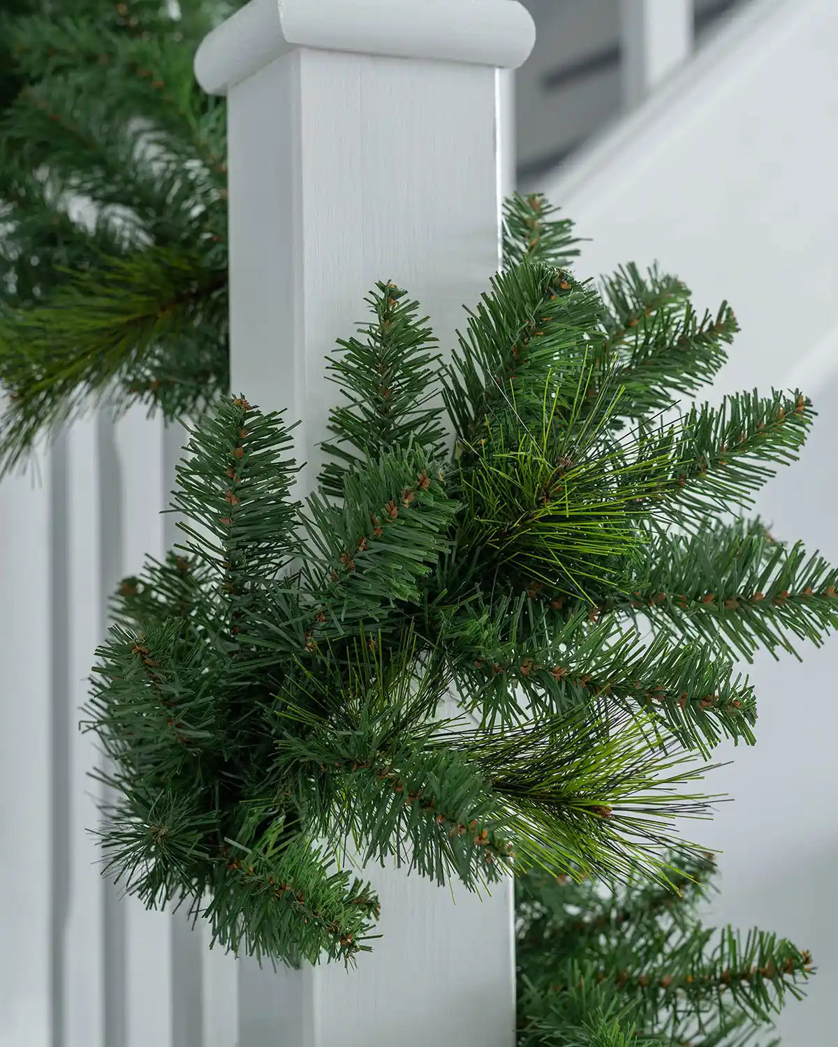 Detail close-up of green artificial garland branches wrapped around a banister