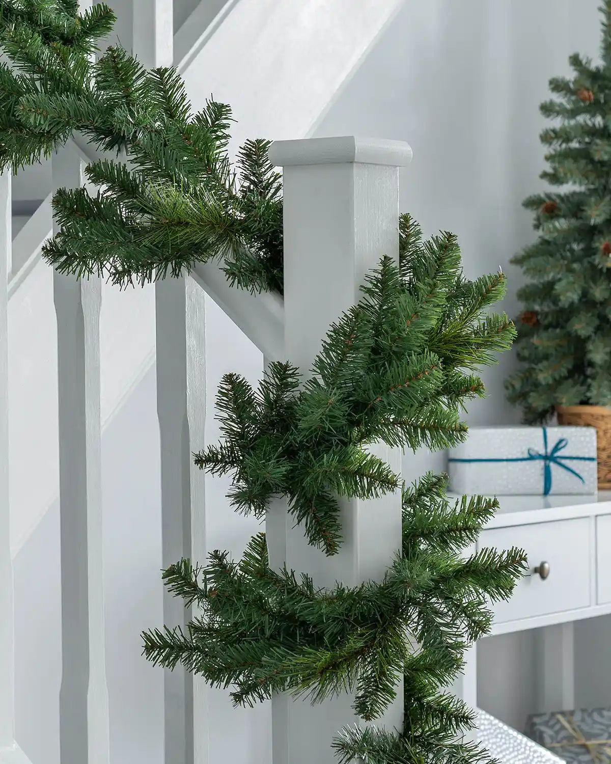Plain green Christmas garland wrapped around a white staircase banister