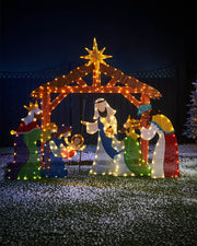 A 2D Tinsel Nativity Scene Silhouette decorated with warm white copper wire LED lights, featuring figures of the nativity story and a manger, set outdoors at night.