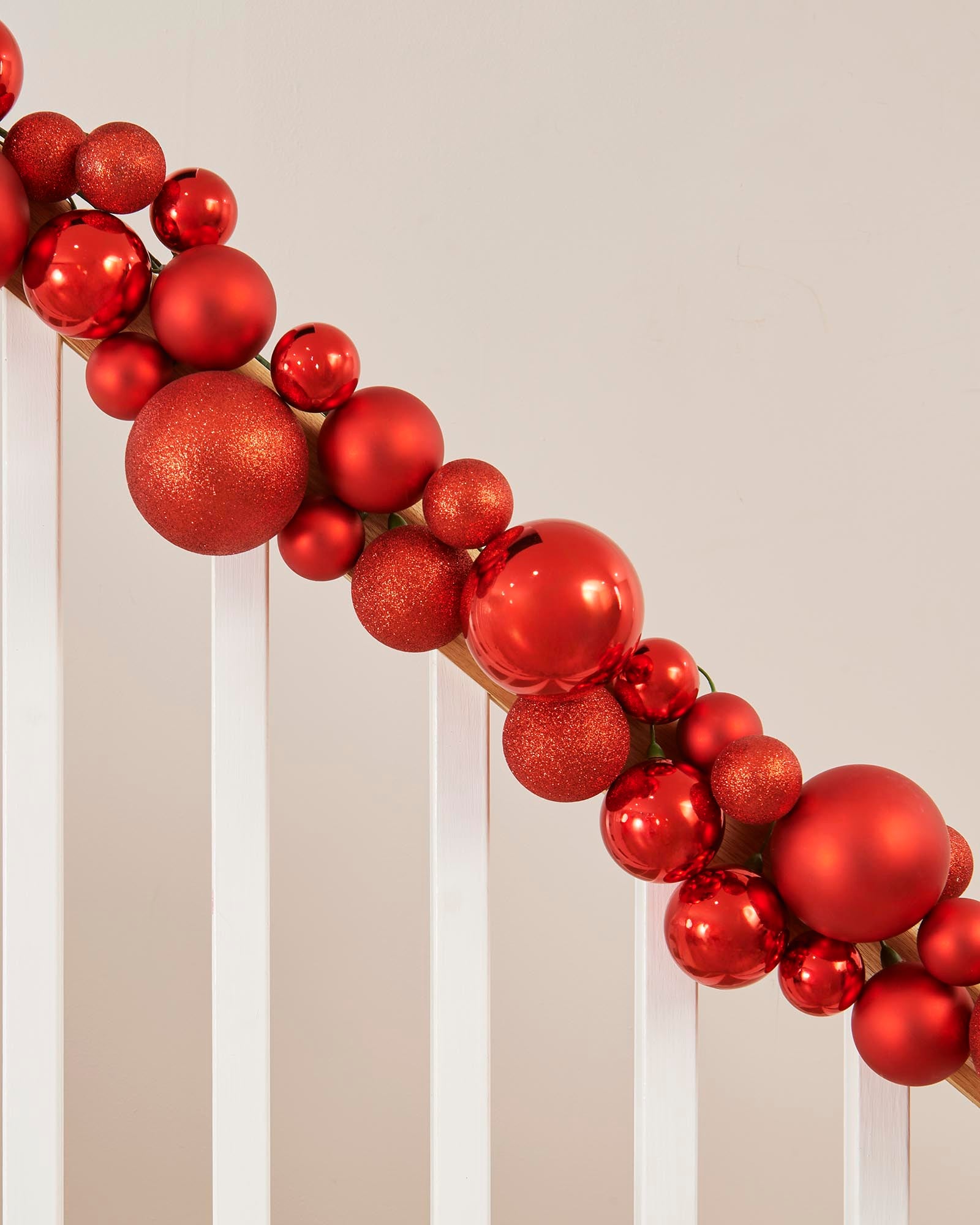 Decorative wreath made of red ornaments on a neutral background