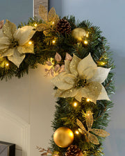 A festive pre-lit extra thick garland with a cream and gold color scheme, featuring LED lights, berries, pine cones, and glittery decorations, displayed against a vertical surface.