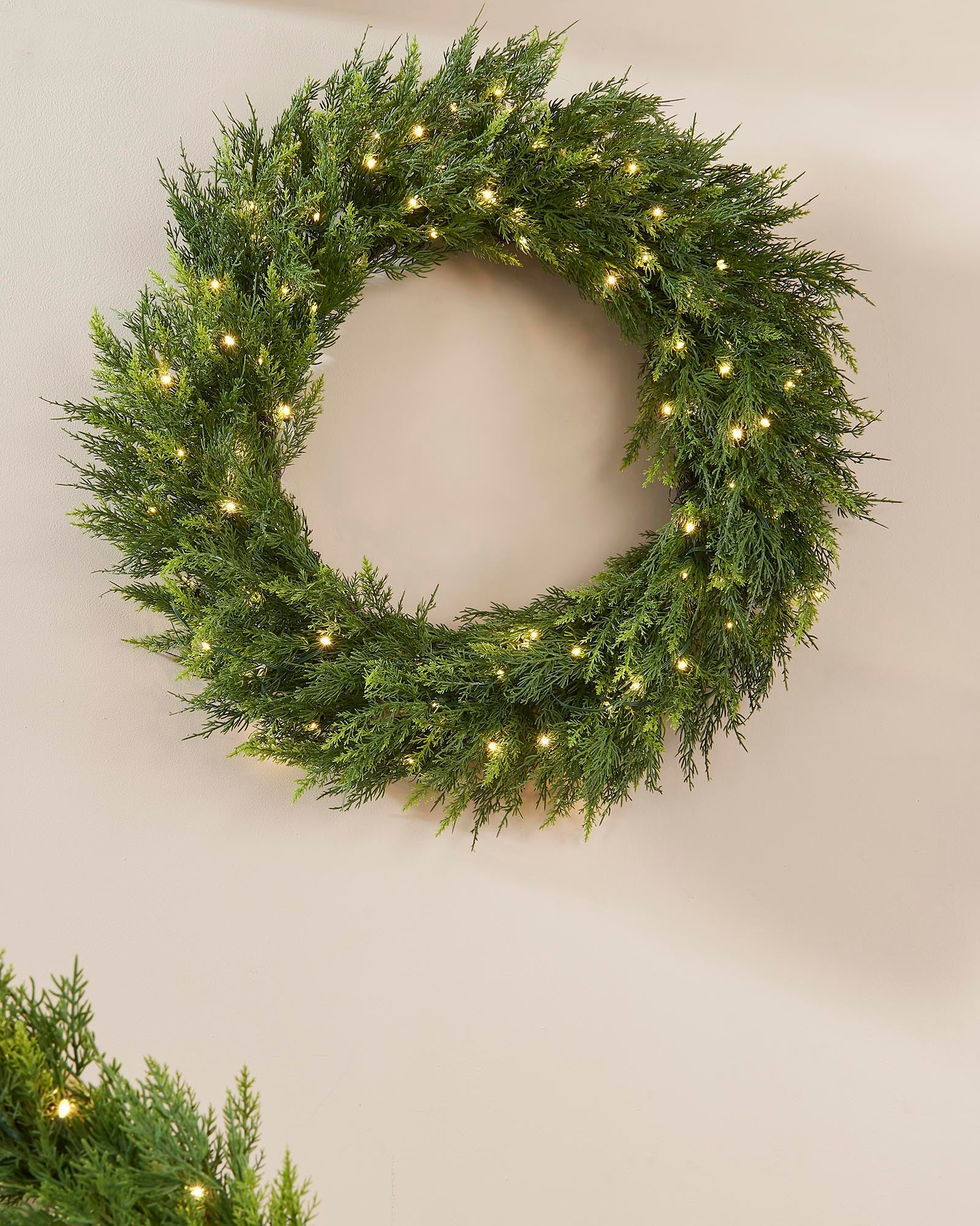 Green wreath with small lights on a plain wall