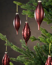Decorative red ornaments hanging on a Christmas tree with a dark background