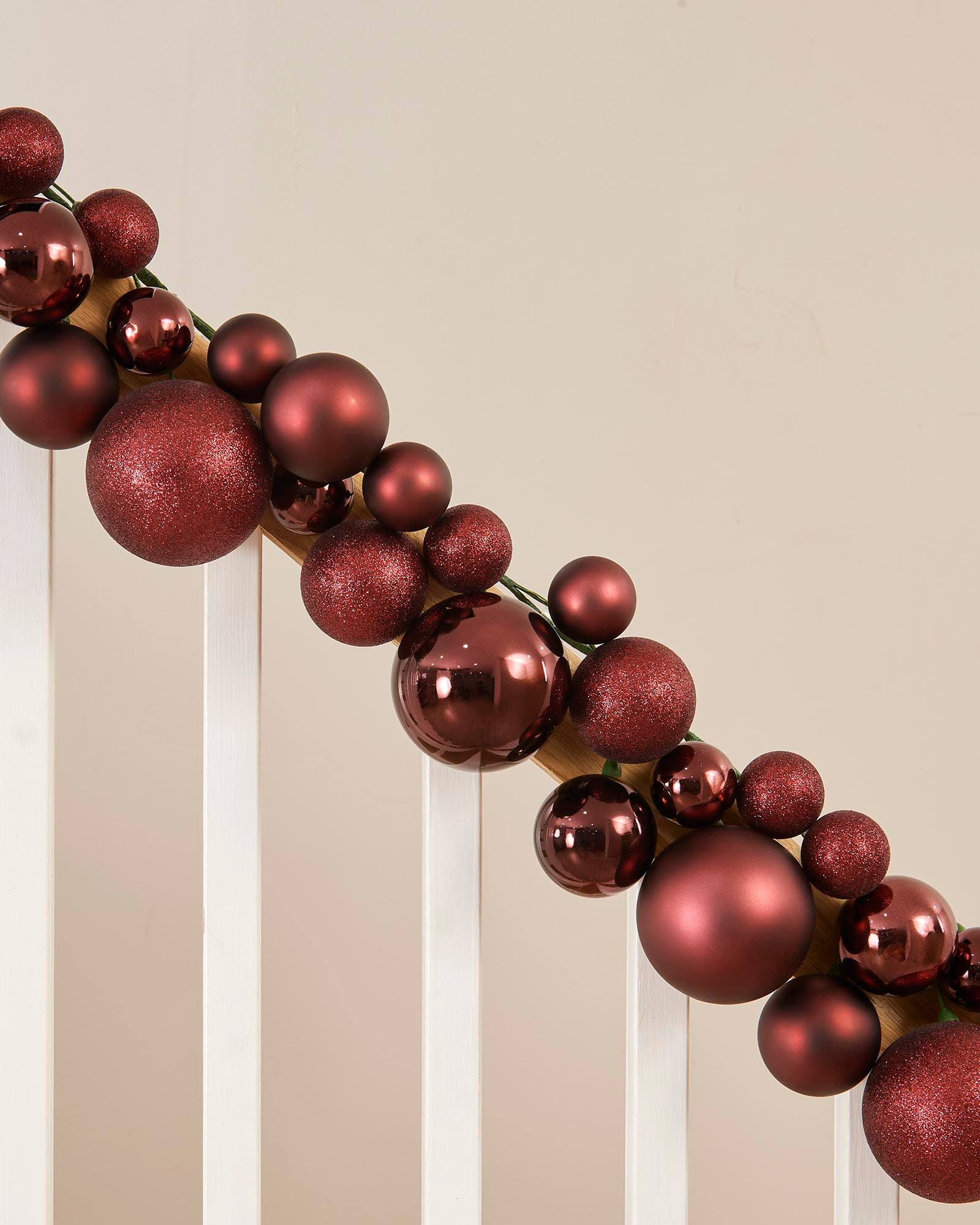 Decorative wreath made of red baubles on a neutral background