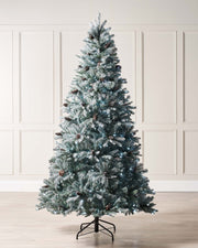 A pre-lit multi-function Christmas tree with mixed PE and PVC branches, adorned with realistic pinecones and a glitter finish, standing indoors. Pre-lit Elegant Spruce artificial Christmas tree with mixed PE and PVC branches, realistic pinecones, glitter finish, and bright white LED lights with multi-function settings, displayed in an indoor setting.