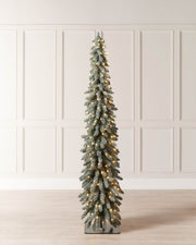 Tall artificial Christmas tree with lights against a white paneled wall.