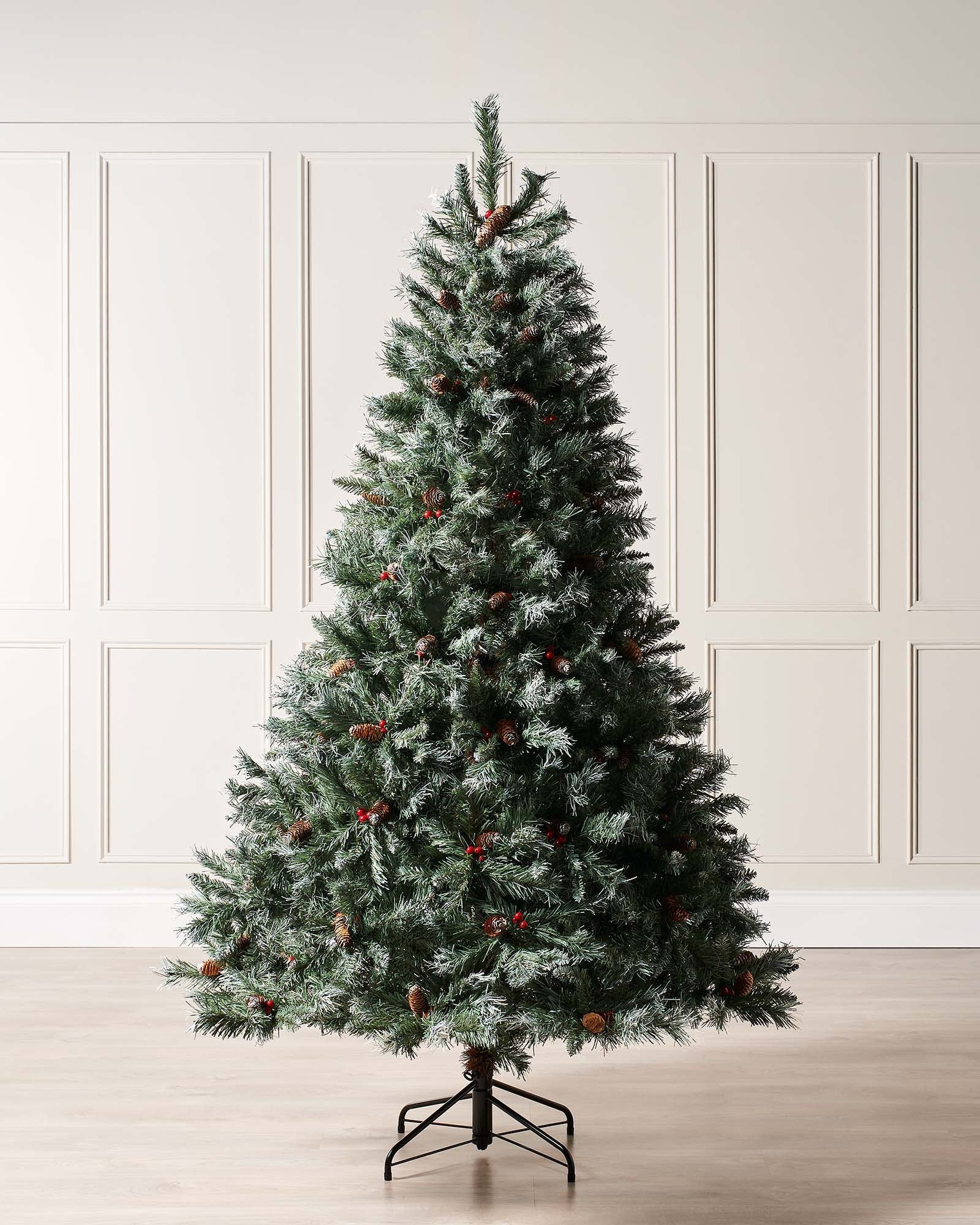 A snow-flocked Scandinavian Blue Spruce Christmas tree adorned with pinecones and red berries, featuring lush, frosted branches that evoke the charm of a Nordic winter forest—perfect for bringing a serene, woodland-inspired festive atmosphere to any indoor space.