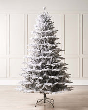 Snow-flocked grey fir artificial Christmas tree with soft grey tones, mixed tips, and a foldable metal stand—featuring a frosted, wintry look that blends traditional charm with modern elegance, perfect for stylish indoor holiday displays.