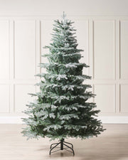 A frosted Siberian Mixed Pine Christmas tree featuring white glitter-tipped branches and fern green foliage, complete with a foldable metal stand. This lifelike, easy-to-assemble tree blends traditional charm with modern elegance, offering a sparkling, customizable canvas for your festive decorations.