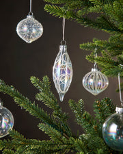 Decorative glass ornaments hanging on a Christmas tree with a dark background