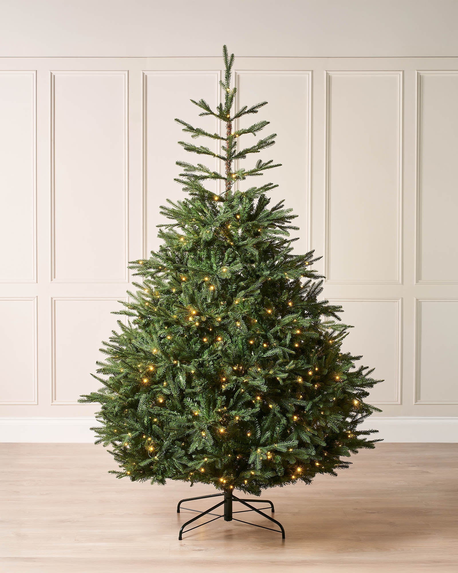 Pre-lit Grand Nordmann Fir Christmas tree with dense PE and PVC branches, warm white LED lights, and elegant pear-shaped silhouette, shown against a neutral background.