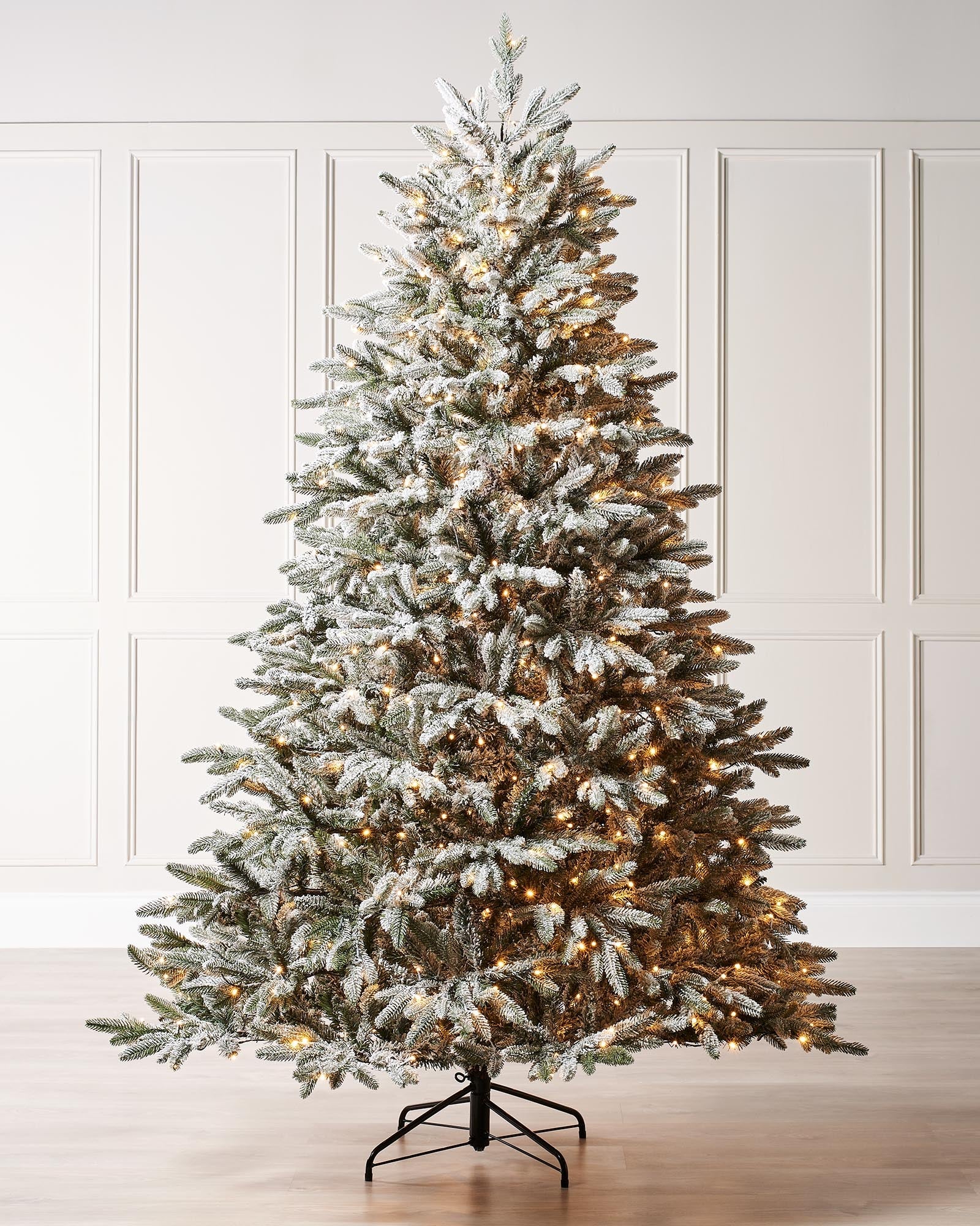 Pre-lit snow flocked Christmas tree with warm white LED lights and mixed PE and PVC branches, displayed against a white background. The tree features a realistic, snowy finish and multi-function lighting for a cozy festive look.