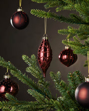 Red glass ornaments on a Christmas tree with a dark background