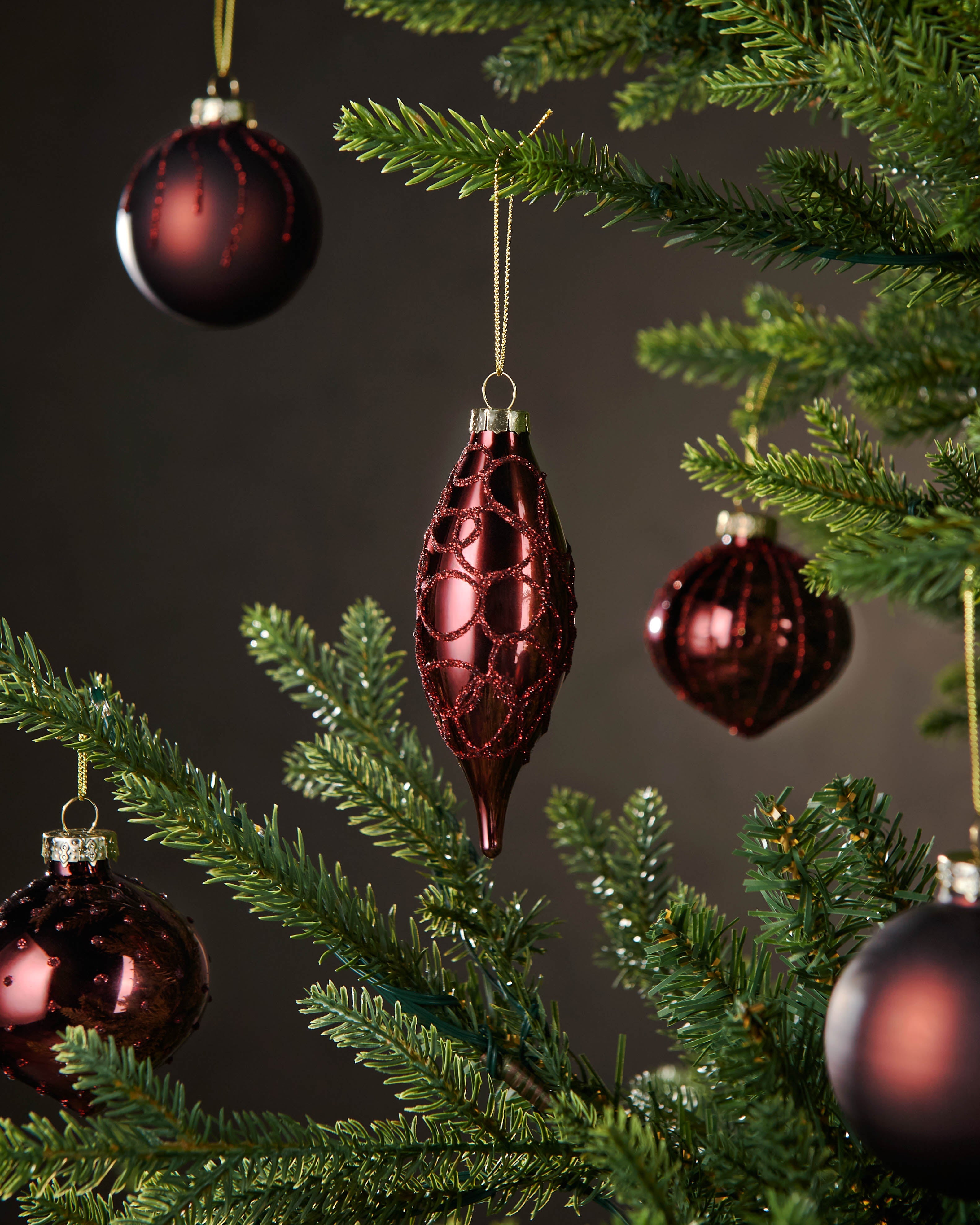 Red glass ornaments on a Christmas tree with a dark background