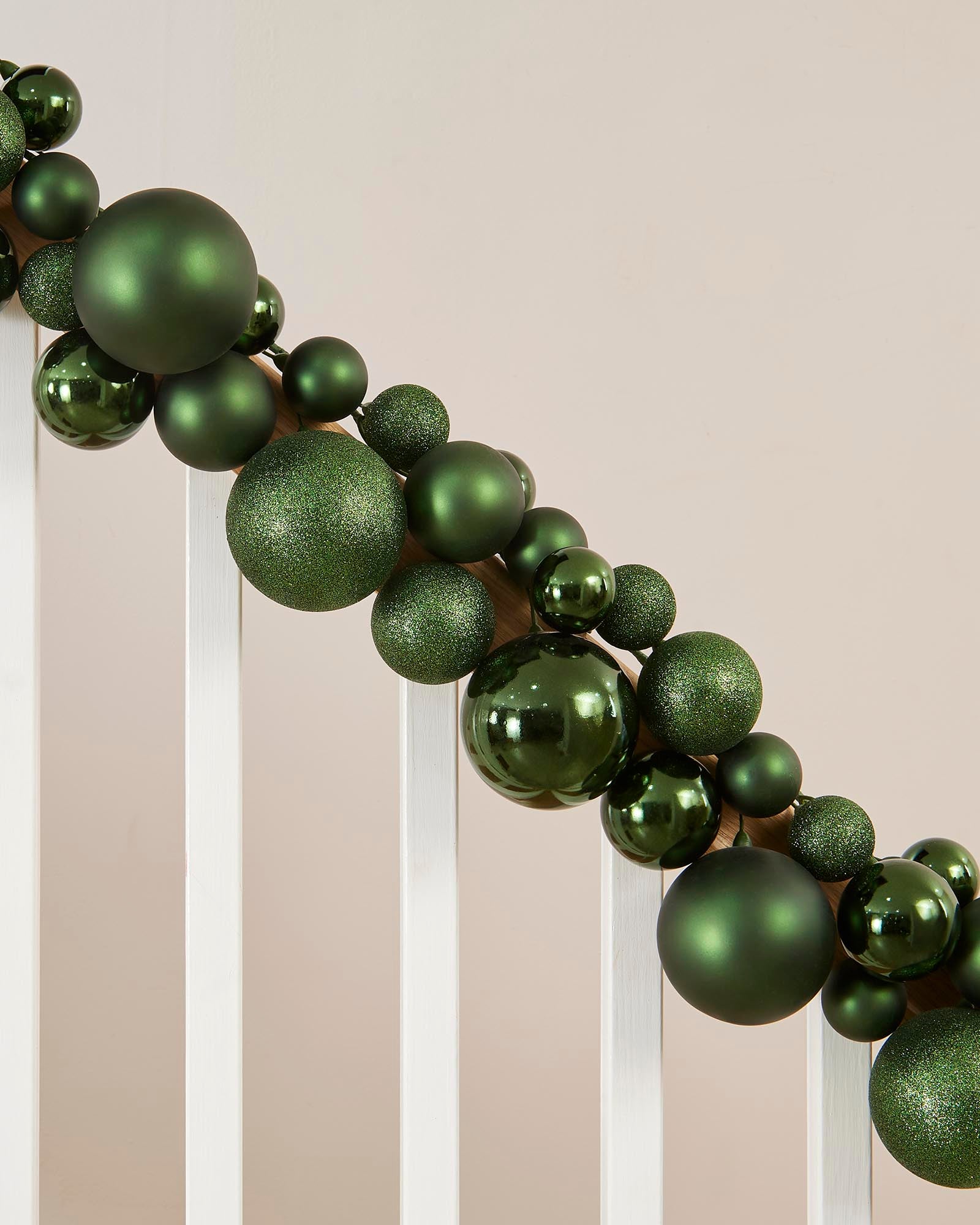 Decorative green ball garland against a neutral background