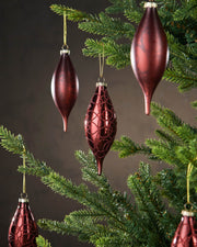 Decorative red ornaments hanging on a Christmas tree with a dark background