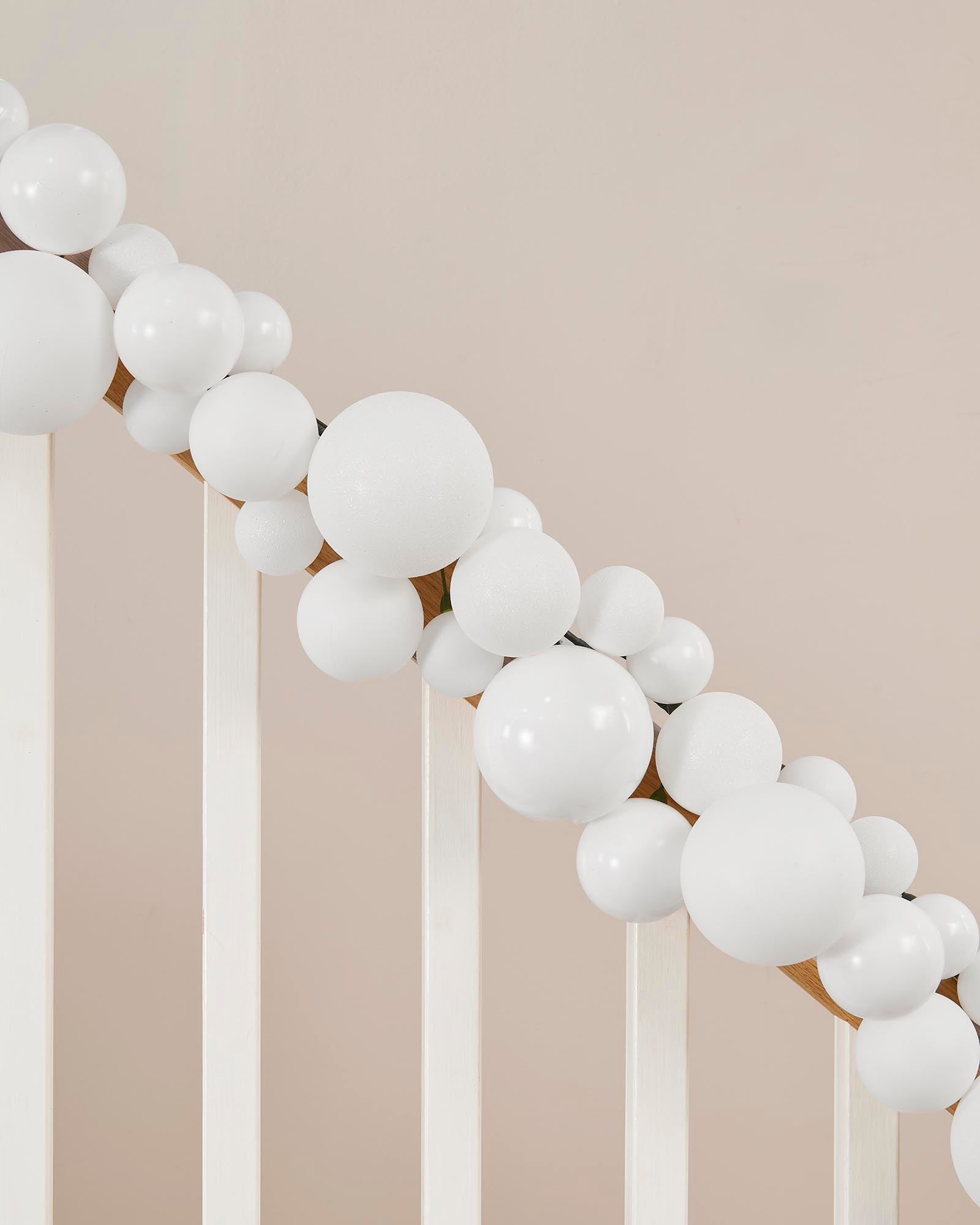Balloon arch made of white balloons against a neutral wall