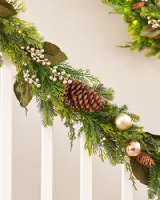 A festive Christmas garland with a mixture of green leaves, pinecones, and gold berries, illuminated by warm white LED lights.