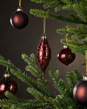 Red glass ornaments on a Christmas tree with a dark background