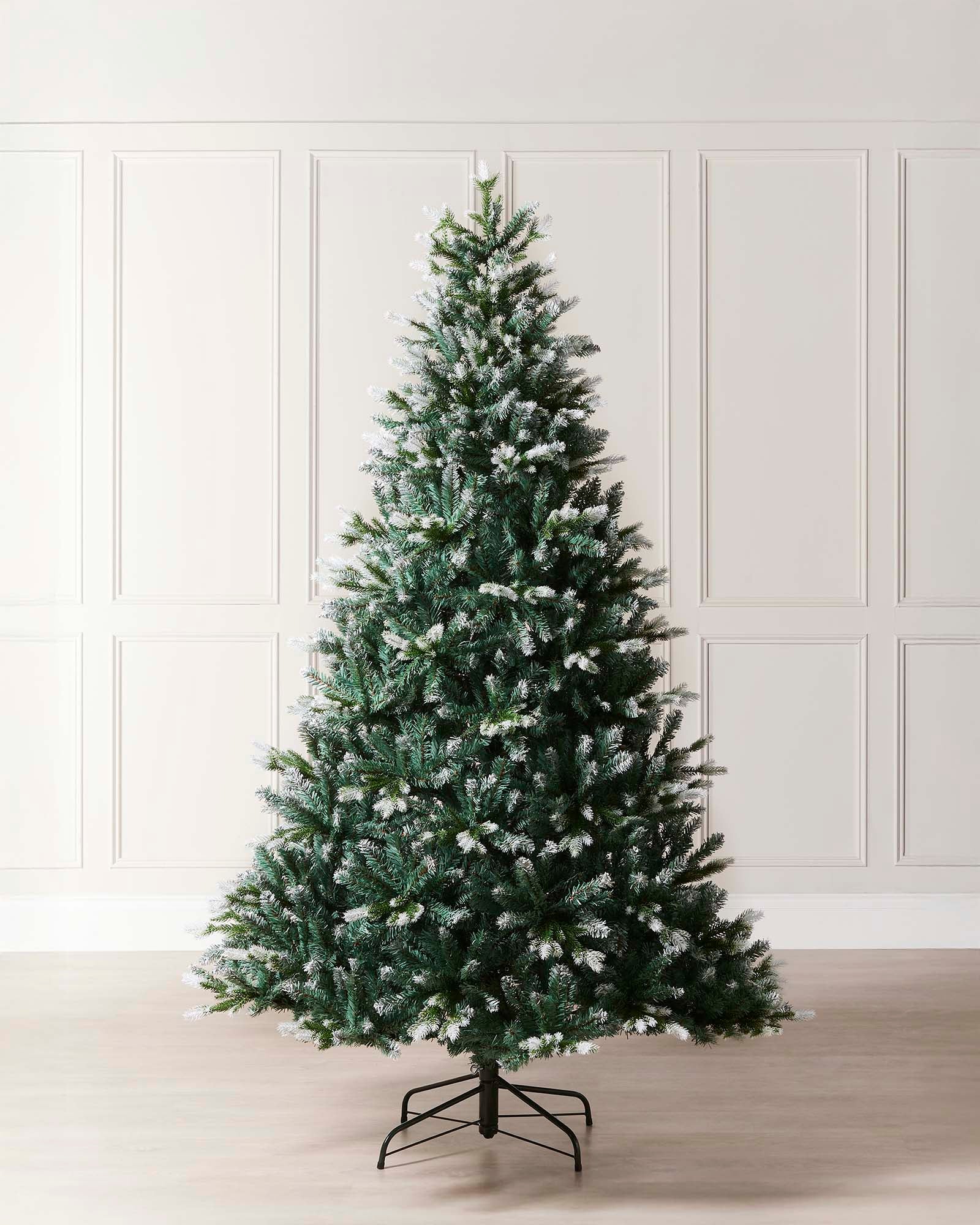 Life-like Evergreen Christmas tree with white snow-flocked tips and mixed cool green and blue tones, featuring hinged branches for easy assembly and storage—perfect for creating a trendy, rustic festive display indoors.