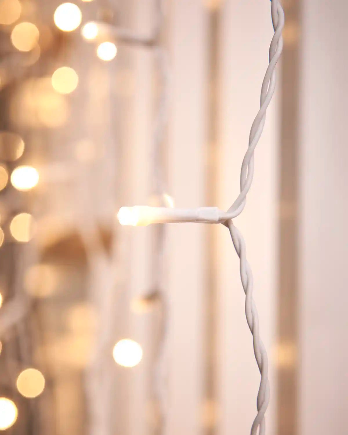 Close-up of a warm white LED on white cable with softly blurred lights behind it.