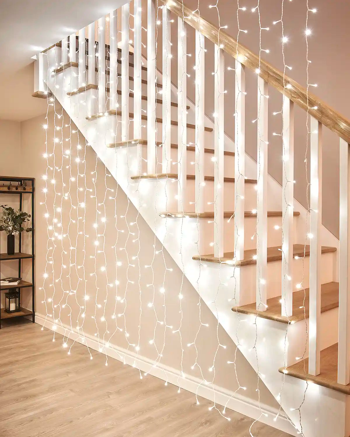 White curtain lights on white cable hanging beside an indoor staircase.