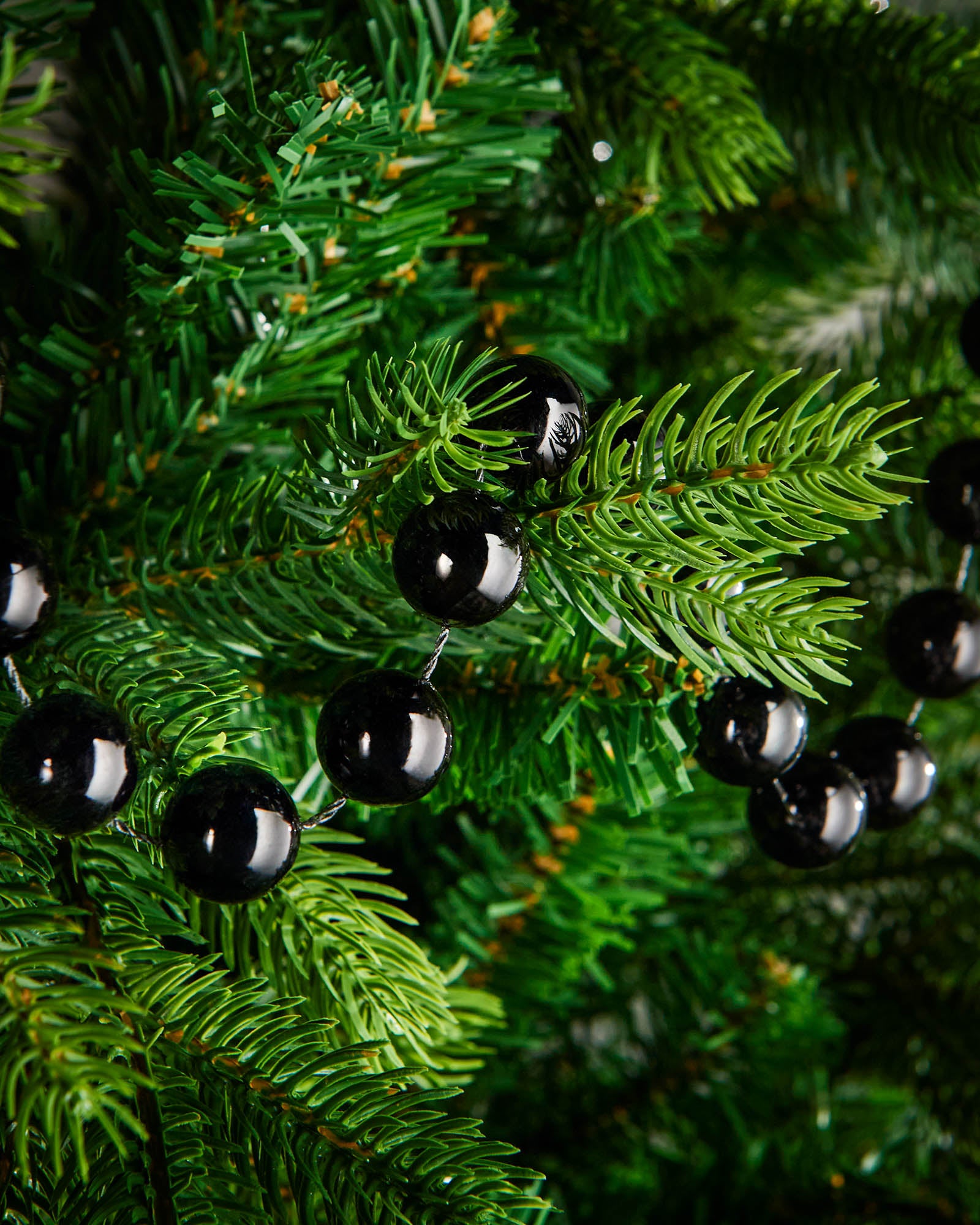 Close-up of glossy black beads on a 2.7m oversized garland displayed on a Christmas tree.