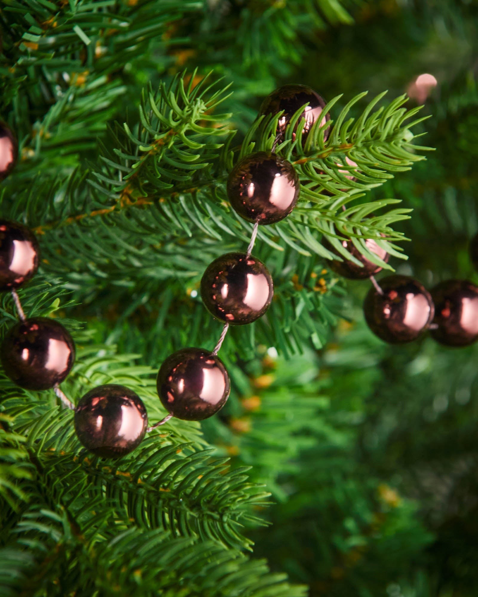Close-up of glossy burgundy beads on a 2.7m oversized garland displayed on a Christmas tree.