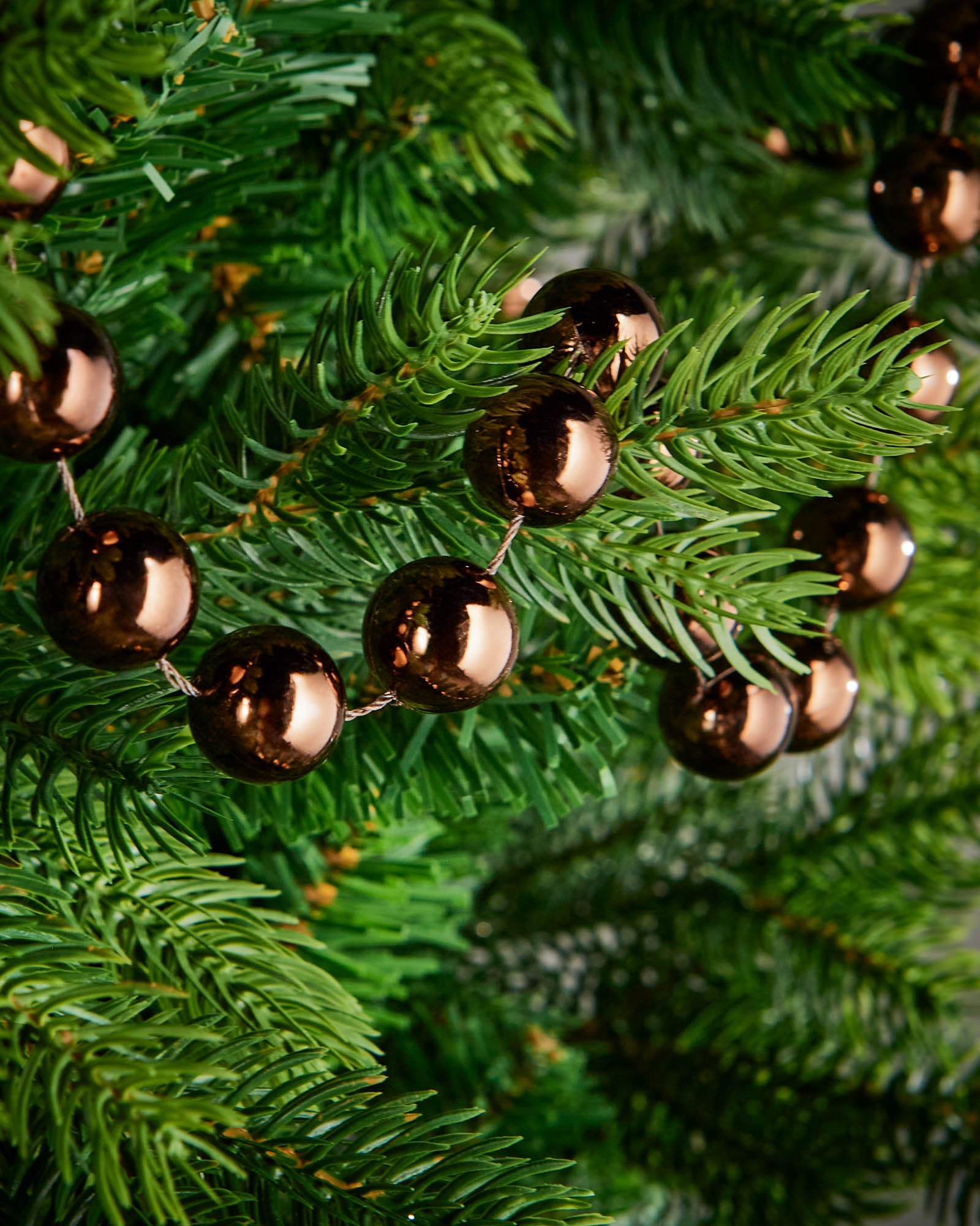 Close-up of glossy espresso beads on a 2.7m oversized garland displayed on a Christmas tree.