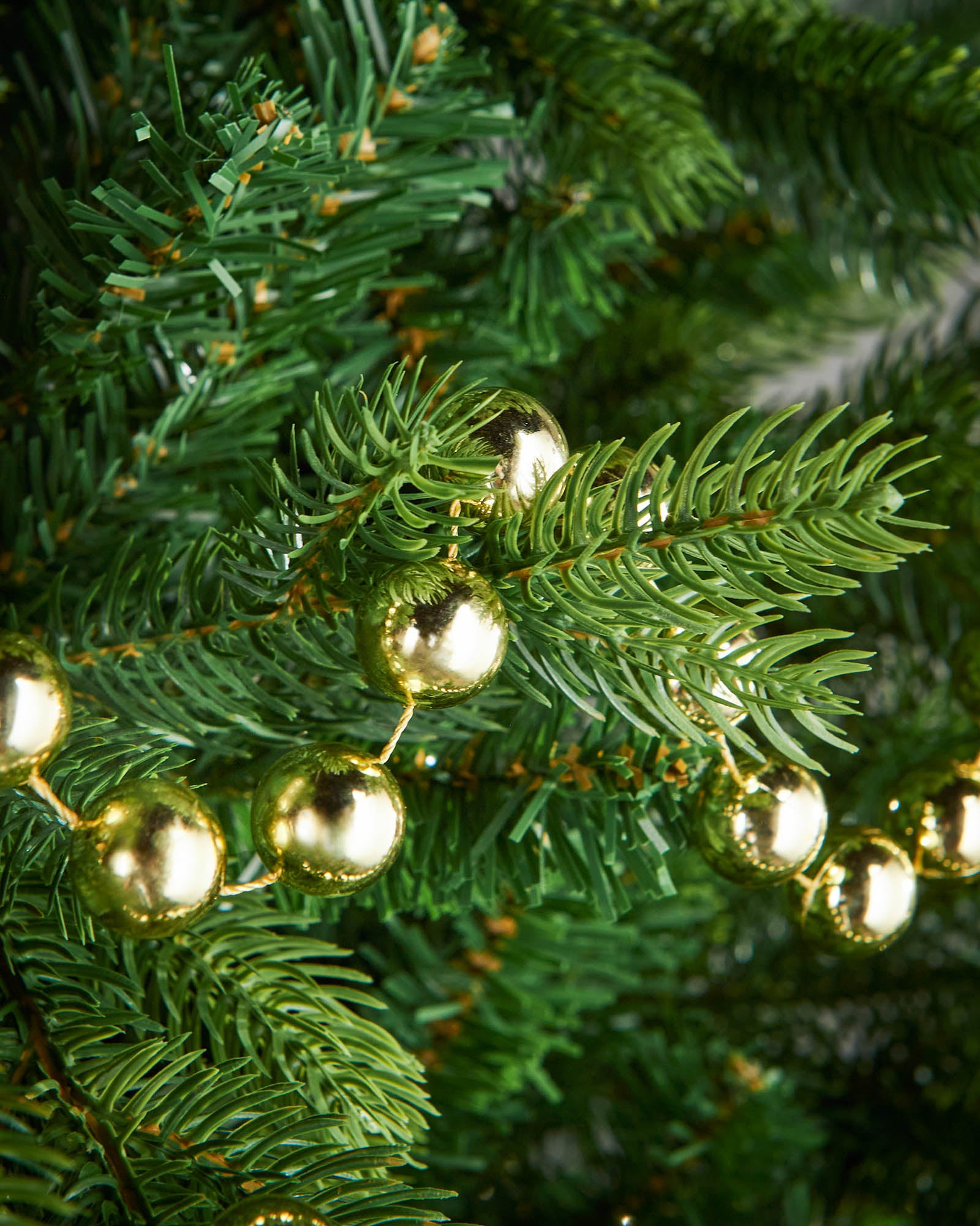 Close-up of glossy gold beads on a 2.7m oversized garland displayed on a Christmas tree.