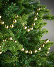 2.7m gold oversized beaded garland draped through green Christmas tree branches.