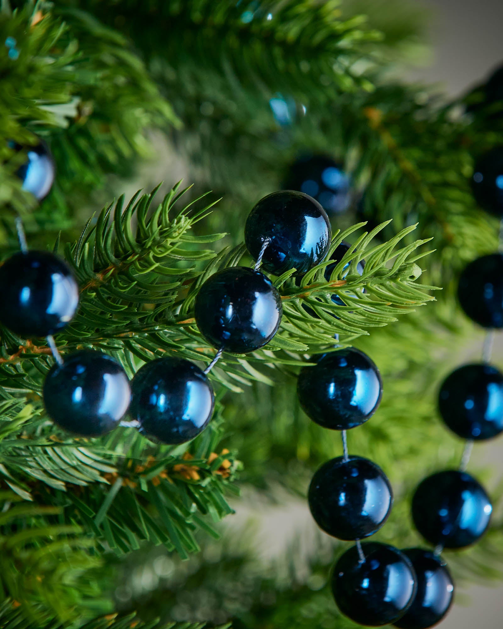 Close-up of glossy navy blue beads on a 2.7m oversized garland displayed on a Christmas tree.