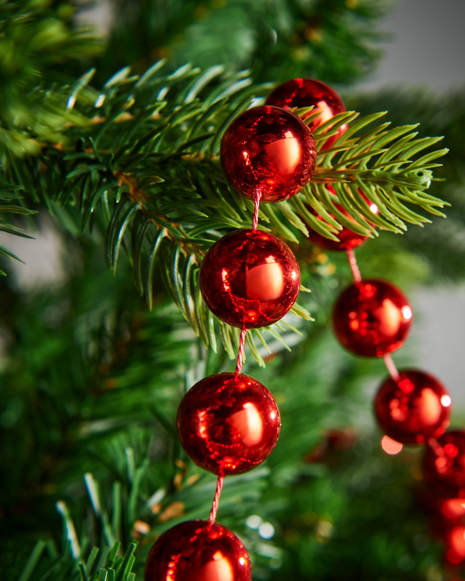 Close-up of glossy red beads on a 2.7m oversized garland displayed on a Christmas tree.