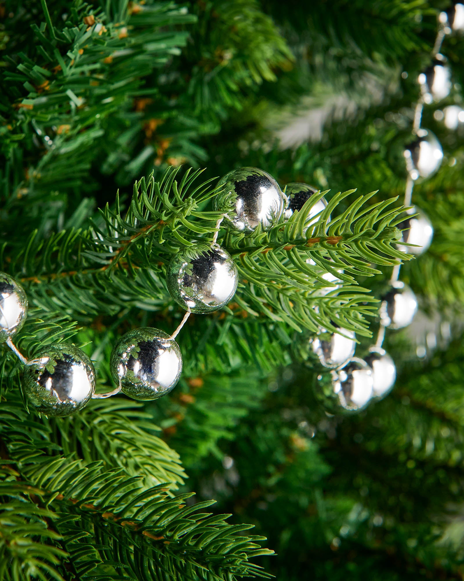 Close-up of glossy silver beads on a 2.7m oversized garland displayed on a Christmas tree.
