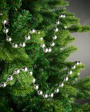 2.7m silver oversized beaded garland draped through green Christmas tree branches.